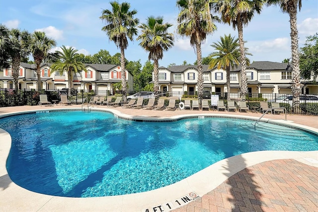 community pool featuring fence, a patio area, and a residential view