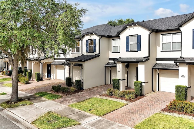 view of property with decorative driveway, a garage, and stucco siding