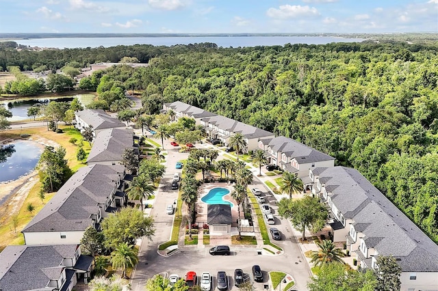 drone / aerial view with a residential view, a water view, and a view of trees