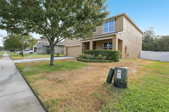view of front of home with a garage, a front lawn, fence, stucco siding, and driveway