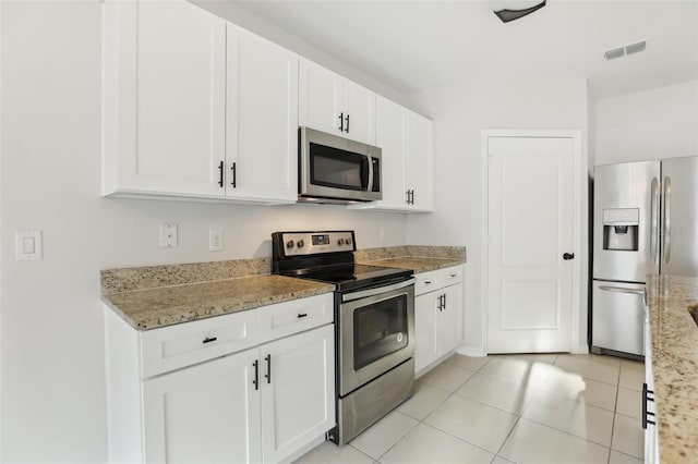 kitchen with visible vents, white cabinets, light stone counters, light tile patterned floors, and stainless steel appliances