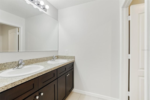 bathroom with a sink, baseboards, tile patterned flooring, and double vanity