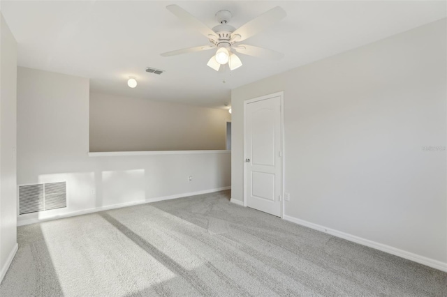 empty room with carpet flooring, ceiling fan, visible vents, and baseboards