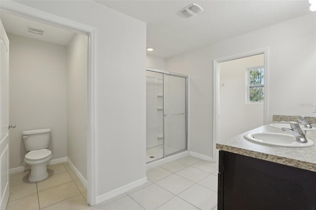 bathroom featuring toilet, tile patterned floors, a shower stall, and a sink