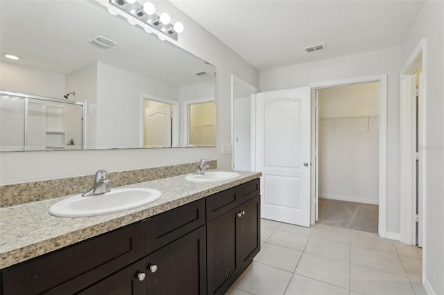 full bath featuring visible vents, a sink, tile patterned floors, and a shower stall