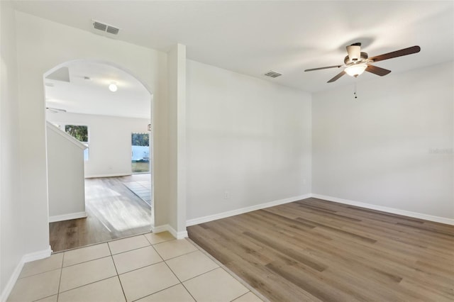 spare room featuring arched walkways, ceiling fan, wood finished floors, and visible vents