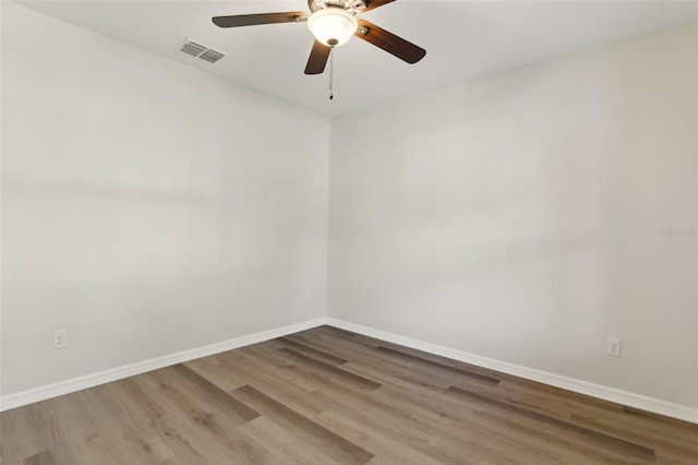 spare room featuring baseboards, ceiling fan, visible vents, and wood finished floors