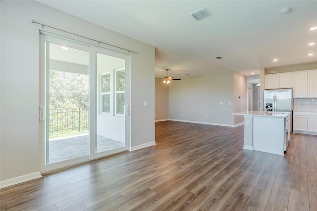507 Daylily Blvd, Nokomis, FL 34275 - kitchen with white cabinetry, wood finished floors, open floor plan, decorative backsplash, and light countertops