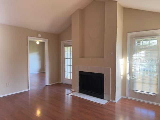 208 Afton Sq Unit 307, Altamonte Springs, FL 32714 - unfurnished living room with lofted ceiling, wood finished floors, healthy amount of natural light, a fireplace, and baseboards