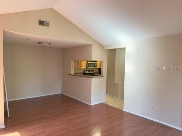 208 Afton Sq Unit 307, Altamonte Springs, FL 32714 - unfurnished living room with lofted ceiling, wood finished floors, and baseboards