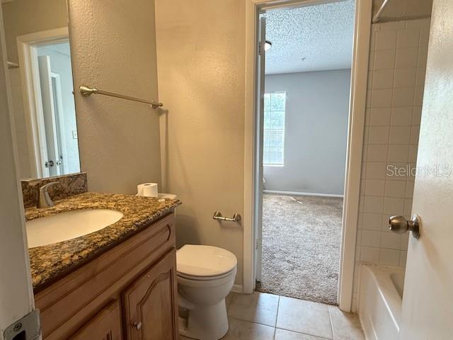 224 Afton Sq Unit 301, Altamonte Springs, FL 32714 - bathroom featuring toilet, a textured ceiling, vanity, tile patterned flooring, and bathing tub / shower combination