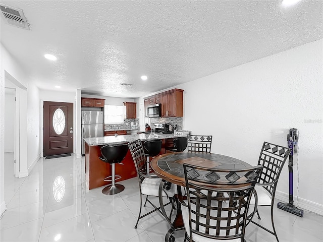 dining room featuring baseboards, visible vents, a textured ceiling, and recessed lighting