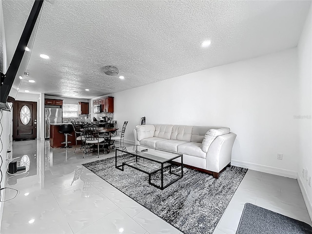 living room featuring recessed lighting, a textured ceiling, marble finish floor, and baseboards