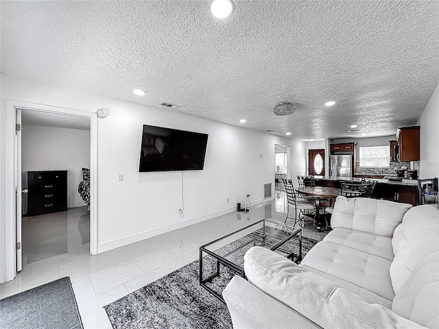 living room featuring recessed lighting, a textured ceiling, visible vents, and baseboards