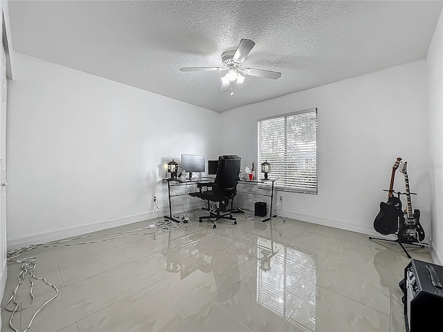home office with marble finish floor, a ceiling fan, a textured ceiling, and baseboards