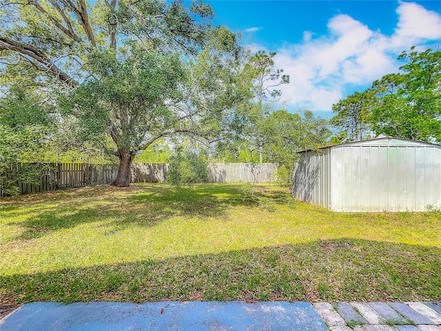 view of yard with a fenced backyard, a shed, and an outbuilding