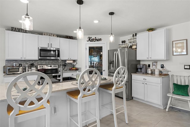 1220 Tahitian Sunrise Dr, Plant City, FL 33565 - kitchen with a breakfast bar area, white cabinets, stainless steel appliances, and pendant lighting