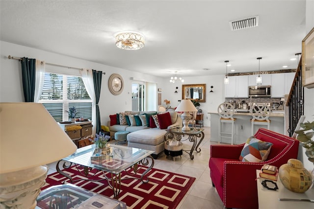 1220 Tahitian Sunrise Dr, Plant City, FL 33565 - living room featuring an inviting chandelier, light tile patterned floors, visible vents, and stairs