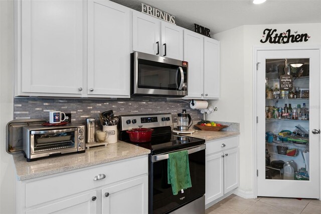 1220 Tahitian Sunrise Dr, Plant City, FL 33565 - kitchen featuring light tile patterned floors, backsplash, appliances with stainless steel finishes, and white cabinetry