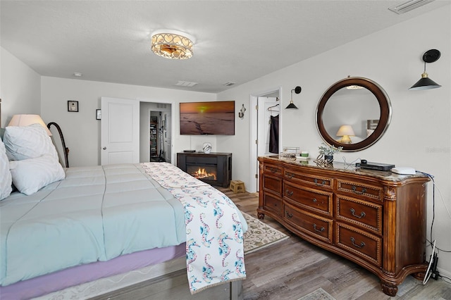 1220 Tahitian Sunrise Dr, Plant City, FL 33565 - bedroom featuring visible vents, wood finished floors, and a glass covered fireplace