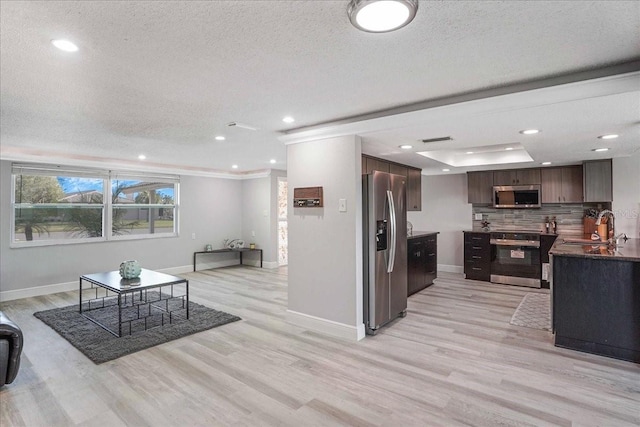 4043 Topsail Trl, New Port Richey, FL 34652 - kitchen with dark brown cabinets, a sink, a textured ceiling, stainless steel appliances, and light wood-type flooring