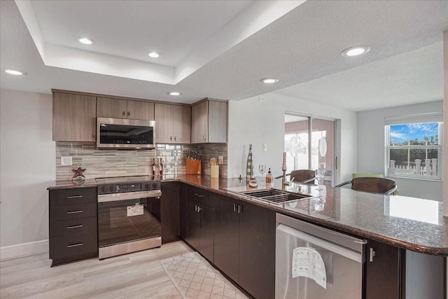 4043 Topsail Trl, New Port Richey, FL 34652 - kitchen featuring decorative backsplash, light wood-type flooring, dark stone countertops, a peninsula, and stainless steel appliances