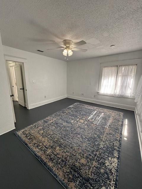 unfurnished room featuring baseboards, ceiling fan, and a textured ceiling
