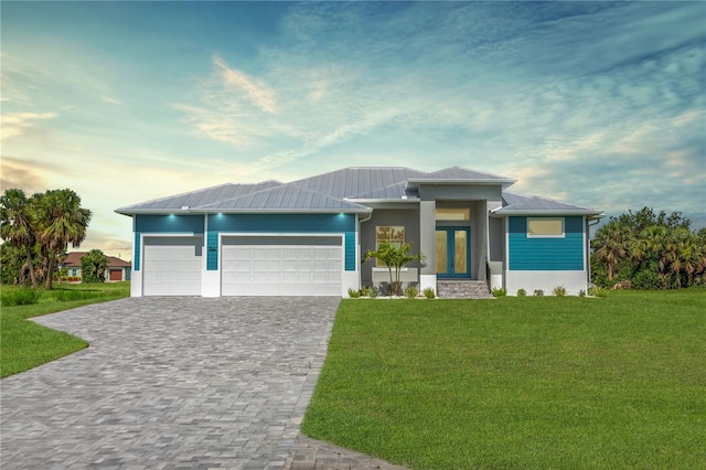 205 Rotonda Blvd S, Rotonda West, FL 33947 - prairie-style house featuring a front yard, an attached garage, decorative driveway, a metal roof, and french doors