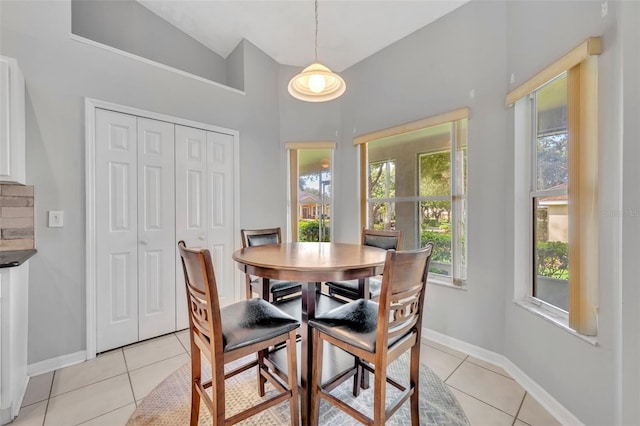 dining room with lofted ceiling, light tile patterned floors, and baseboards