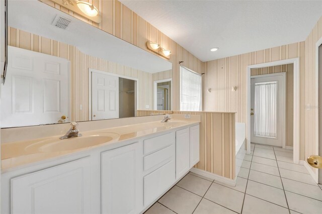 bathroom with double vanity, tile patterned flooring, wallpapered walls, and a sink