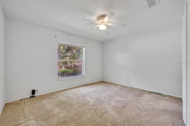carpeted empty room with visible vents, a ceiling fan, and baseboards