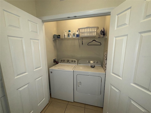 clothes washing area with light tile patterned floors, independent washer and dryer, and laundry area