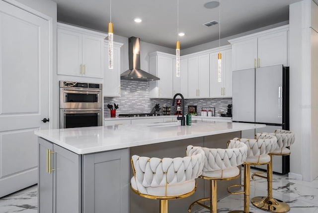 kitchen with tasteful backsplash, visible vents, stainless steel double oven, wall chimney exhaust hood, and marble finish floor