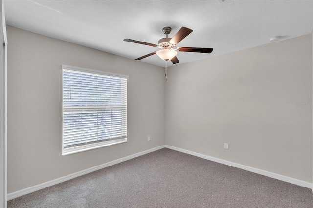 carpeted empty room featuring a ceiling fan and baseboards