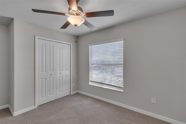 unfurnished bedroom with carpet floors, baseboards, a ceiling fan, and a closet
