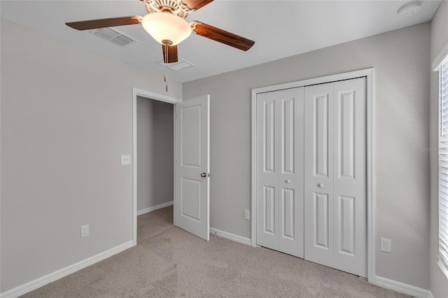 unfurnished bedroom with visible vents, a closet, baseboards, light colored carpet, and a ceiling fan