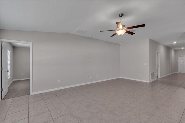 empty room with baseboards, ceiling fan, vaulted ceiling, and visible vents