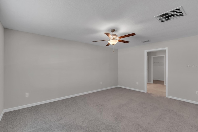 unfurnished room with a ceiling fan, baseboards, visible vents, and light carpet