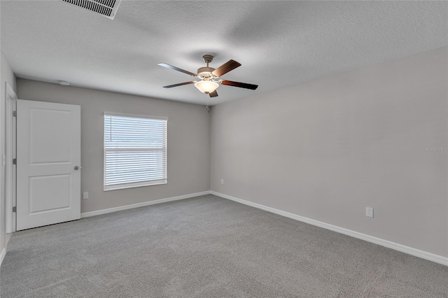 carpeted spare room featuring baseboards, ceiling fan, a textured ceiling, and visible vents
