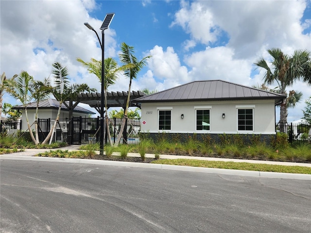 exterior space featuring metal roof, stucco siding, fence, and a standing seam roof