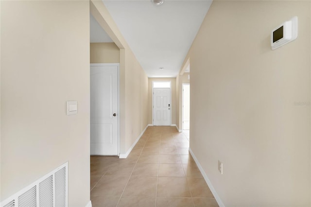 hallway featuring light tile patterned floors, visible vents, and baseboards