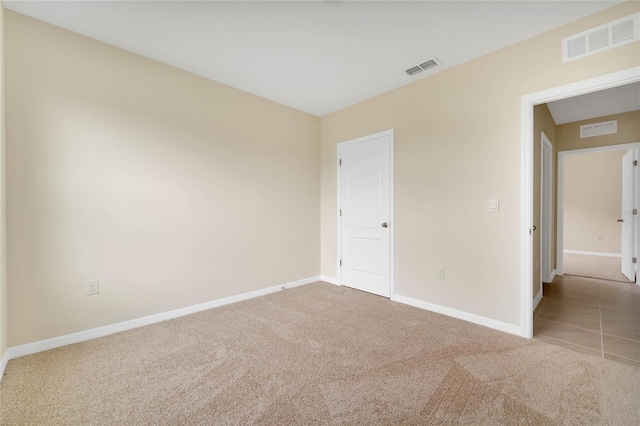 carpeted empty room featuring visible vents and baseboards