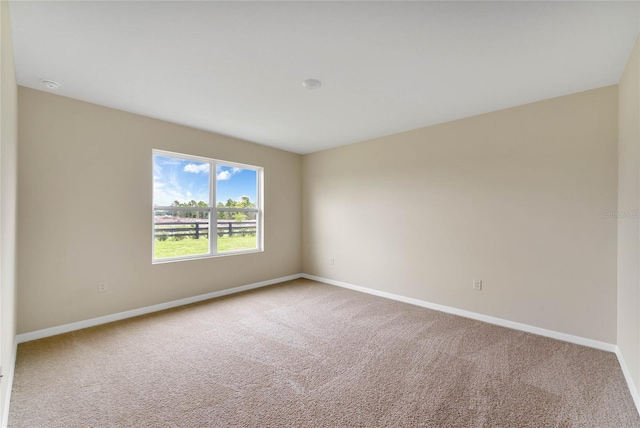 carpeted empty room featuring baseboards