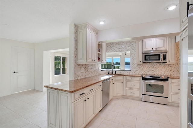 kitchen with a sink, light tile patterned floors, backsplash, and stainless steel appliances