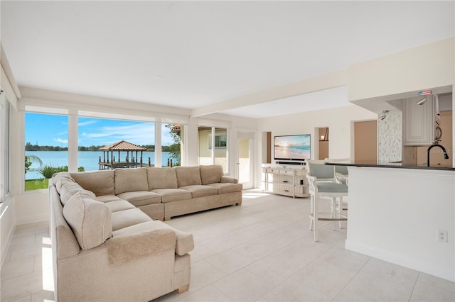 living room with light tile patterned floors, a water view, and baseboards