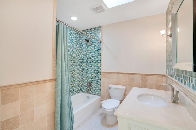 bathroom featuring toilet, tile patterned floors, shower / bathtub combination with curtain, tile walls, and visible vents