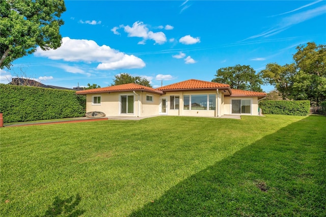 back of property with a yard, a tiled roof, and stucco siding