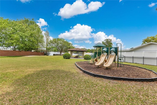 community play area with a lawn, a gazebo, and fence