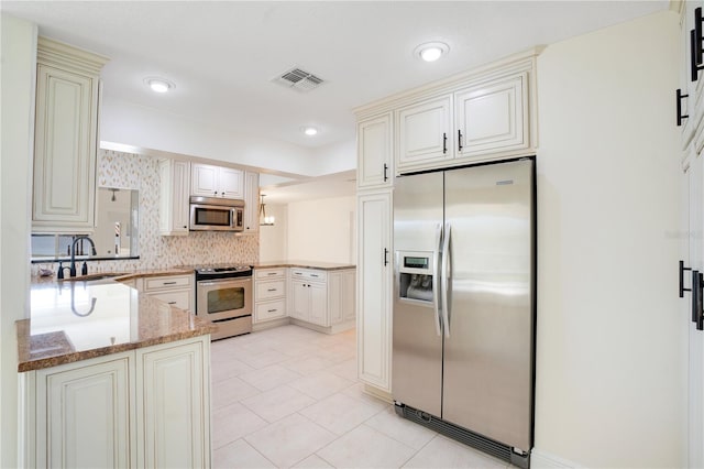 kitchen with light tile patterned flooring, light stone countertops, appliances with stainless steel finishes, a sink, and visible vents