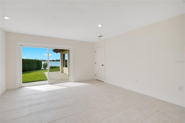 empty room with visible vents, baseboards, recessed lighting, a water view, and light tile patterned floors